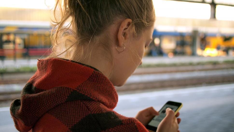 Traveller checking a phone at a busy train station
